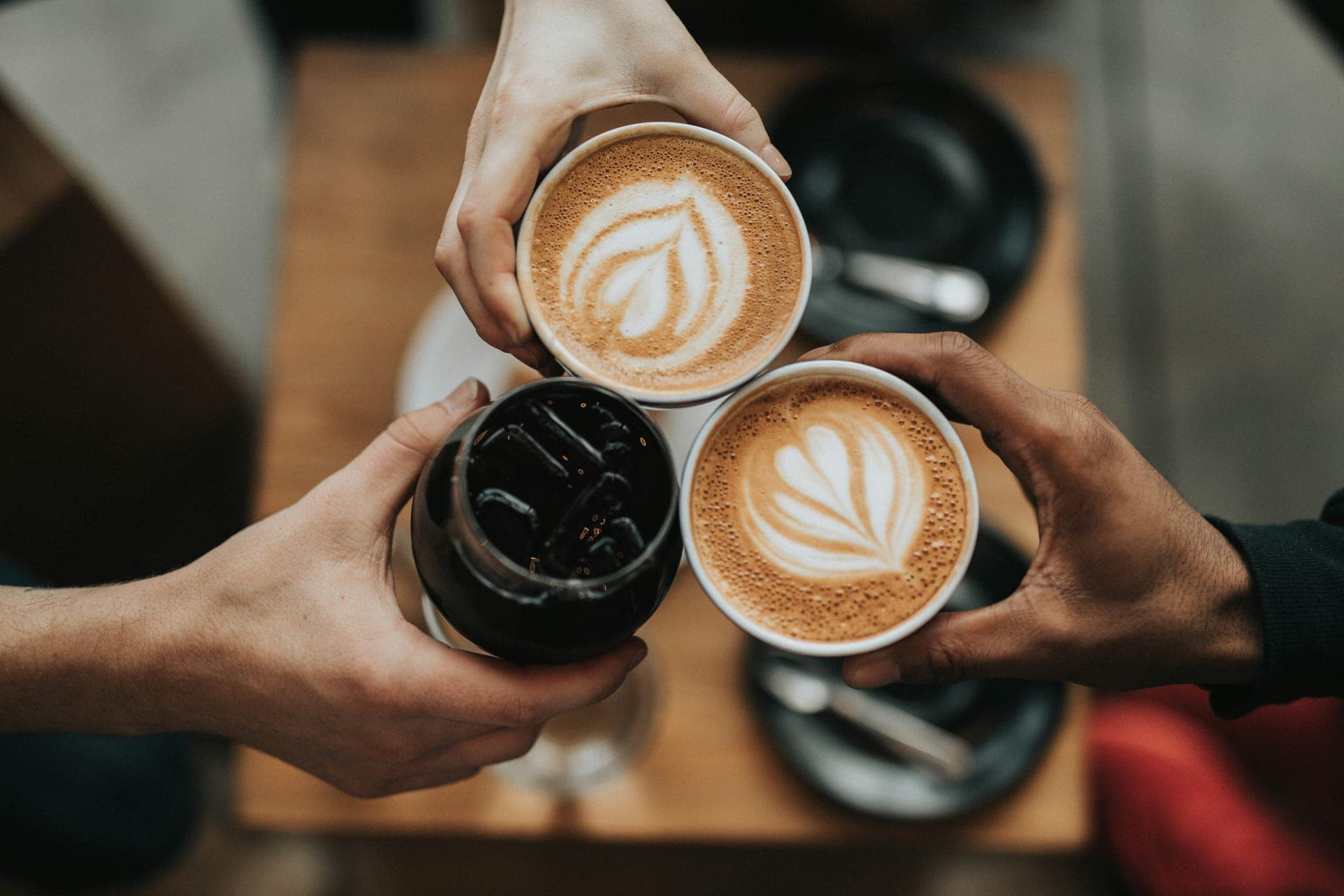 Three friends raising coffee cups together
