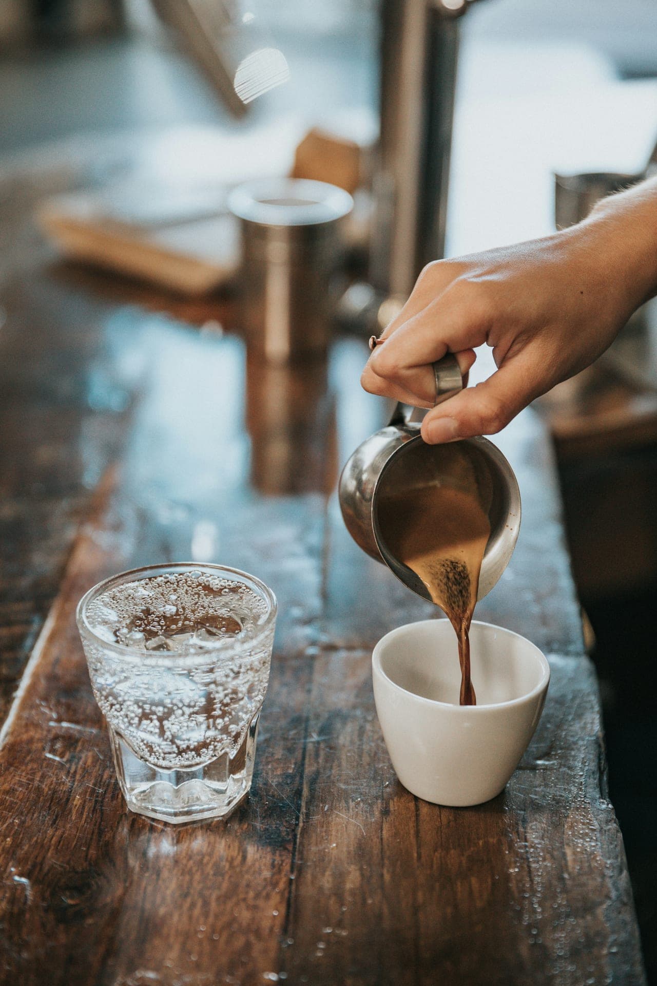 Espresso poured beside a glass of sparkling water